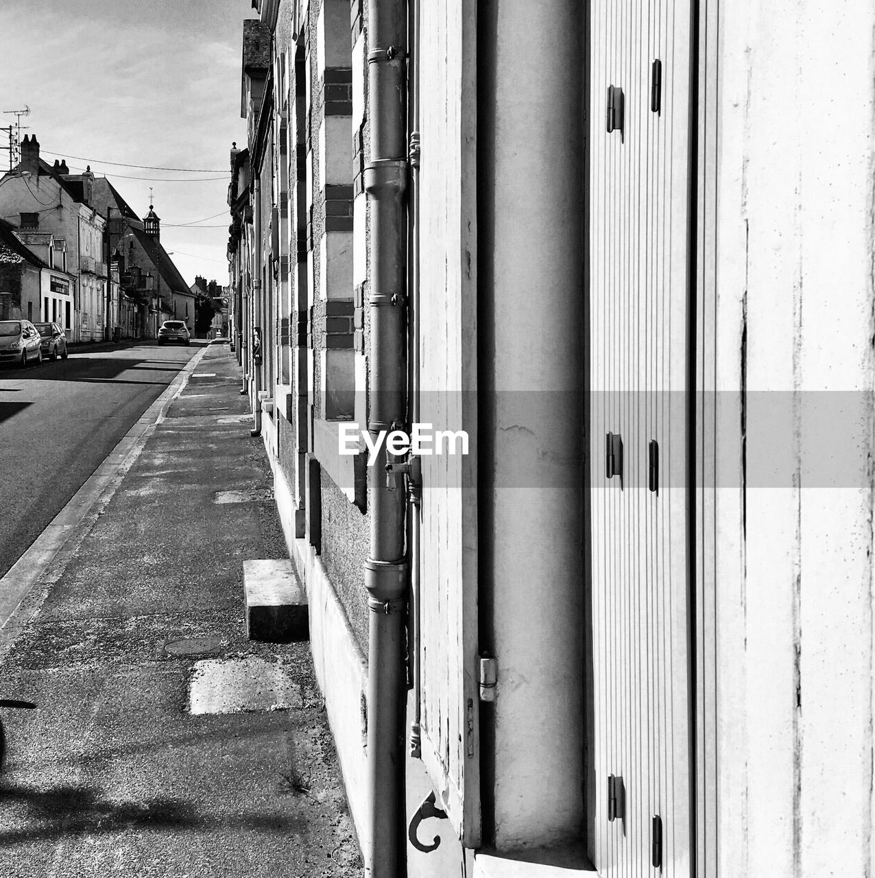 EMPTY ROAD BY BUILDINGS AGAINST SKY