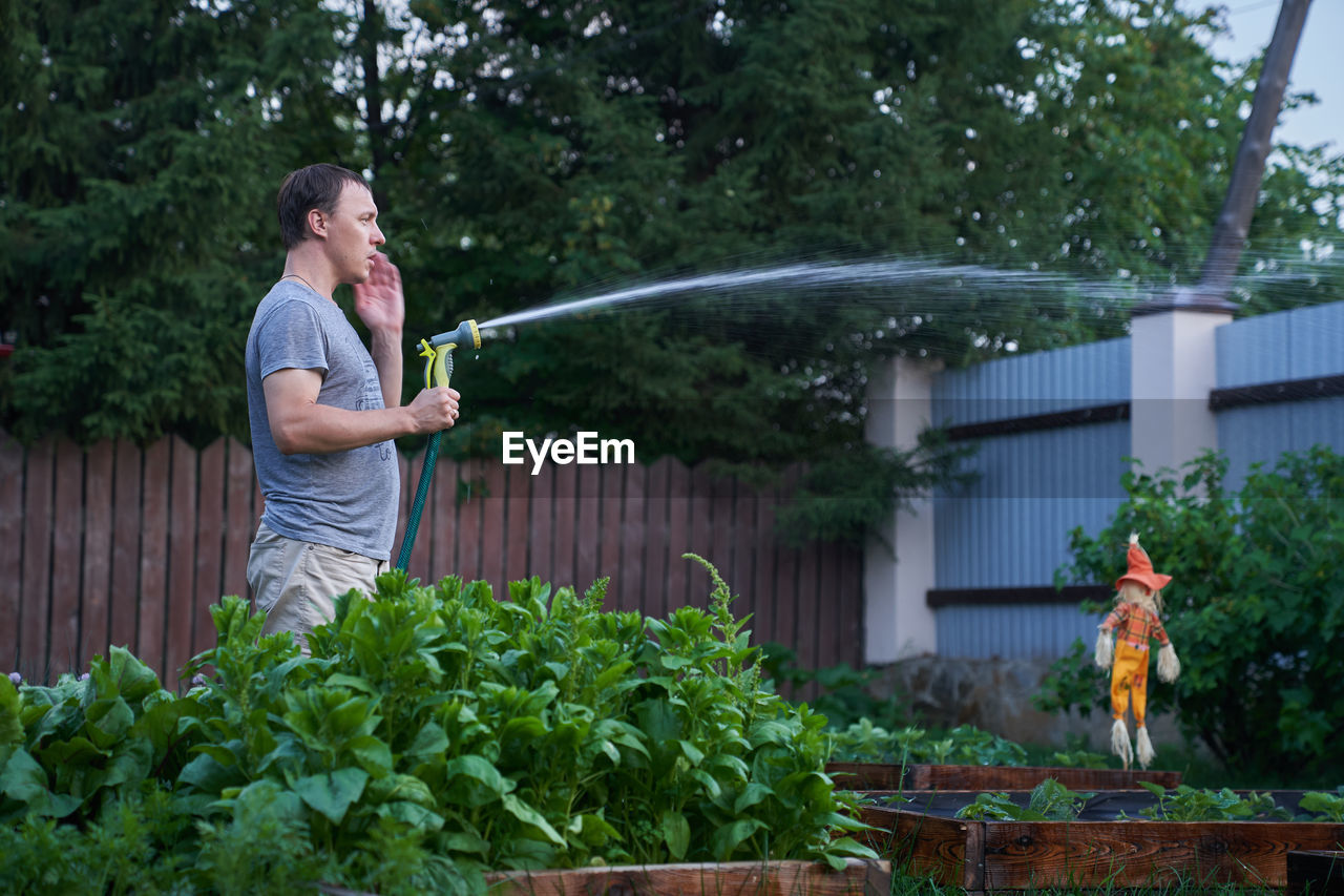 Man watering plant at garden