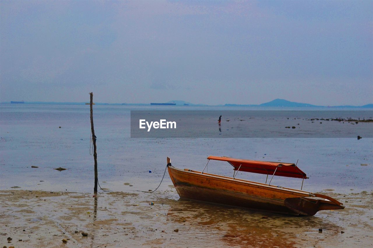 Boat moored at beach against sky