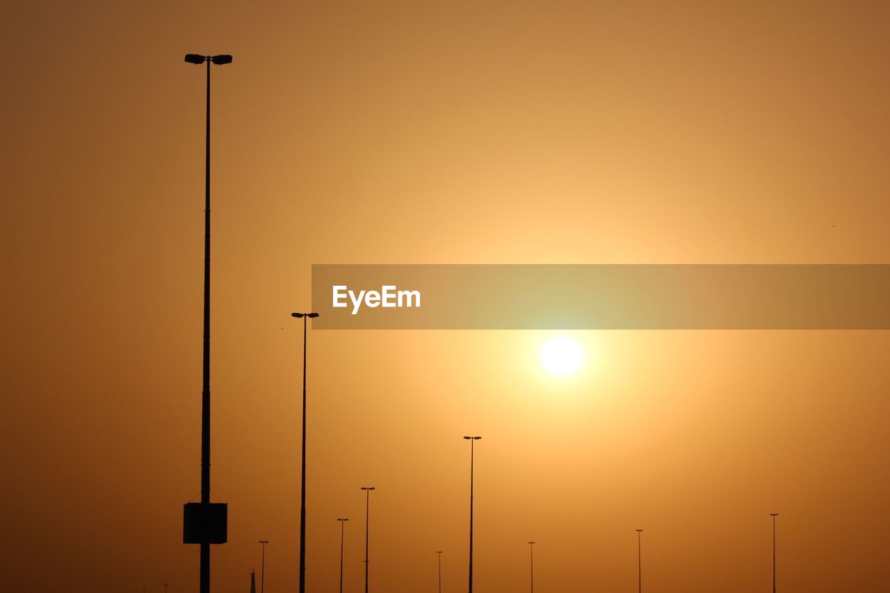 SILHOUETTE STREET LIGHT AGAINST ORANGE SKY DURING SUNSET