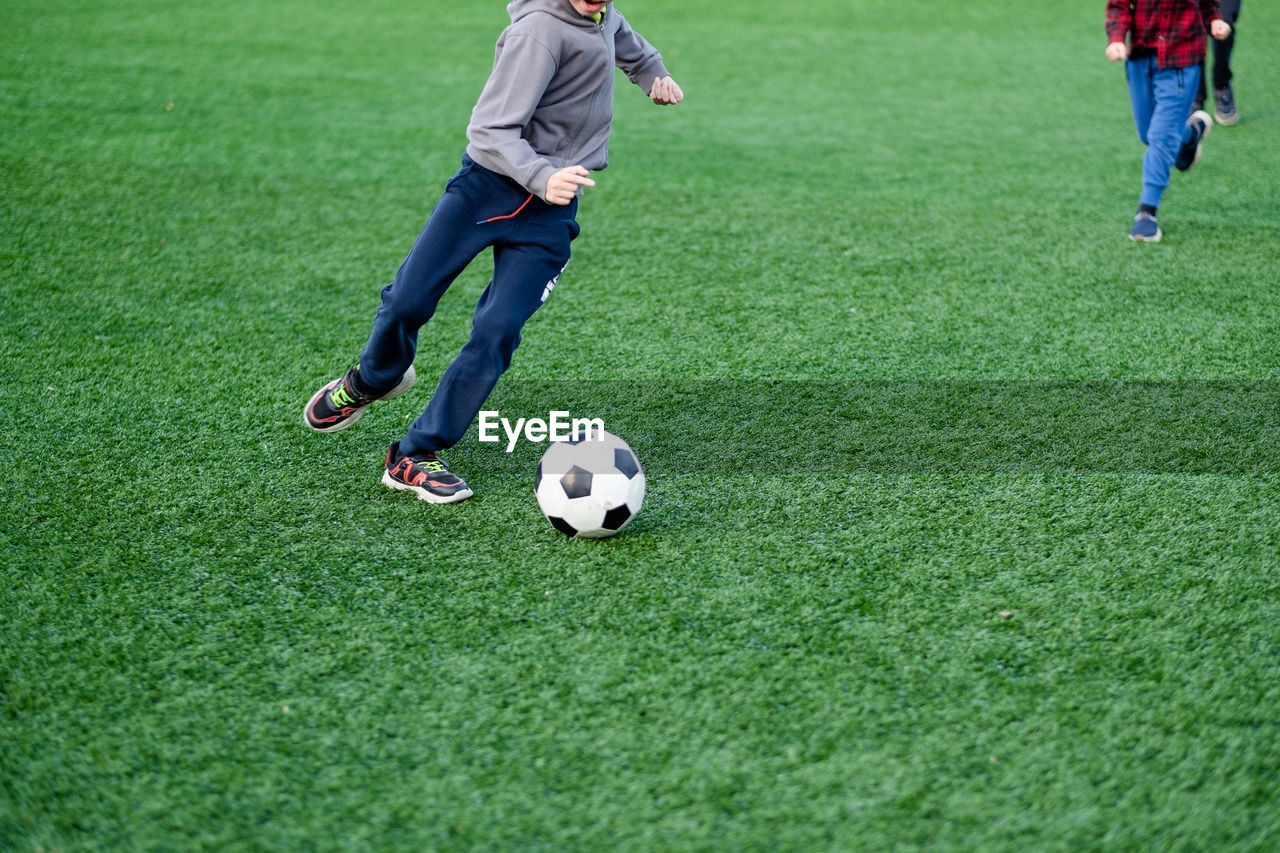 The boy plays football in the yard, on the lawn. child kicks the ball close up