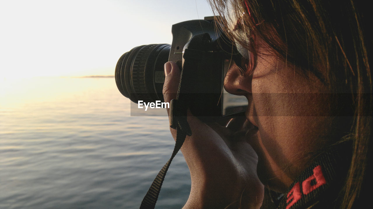 Close-up of woman photographing with camera at beach during sunset