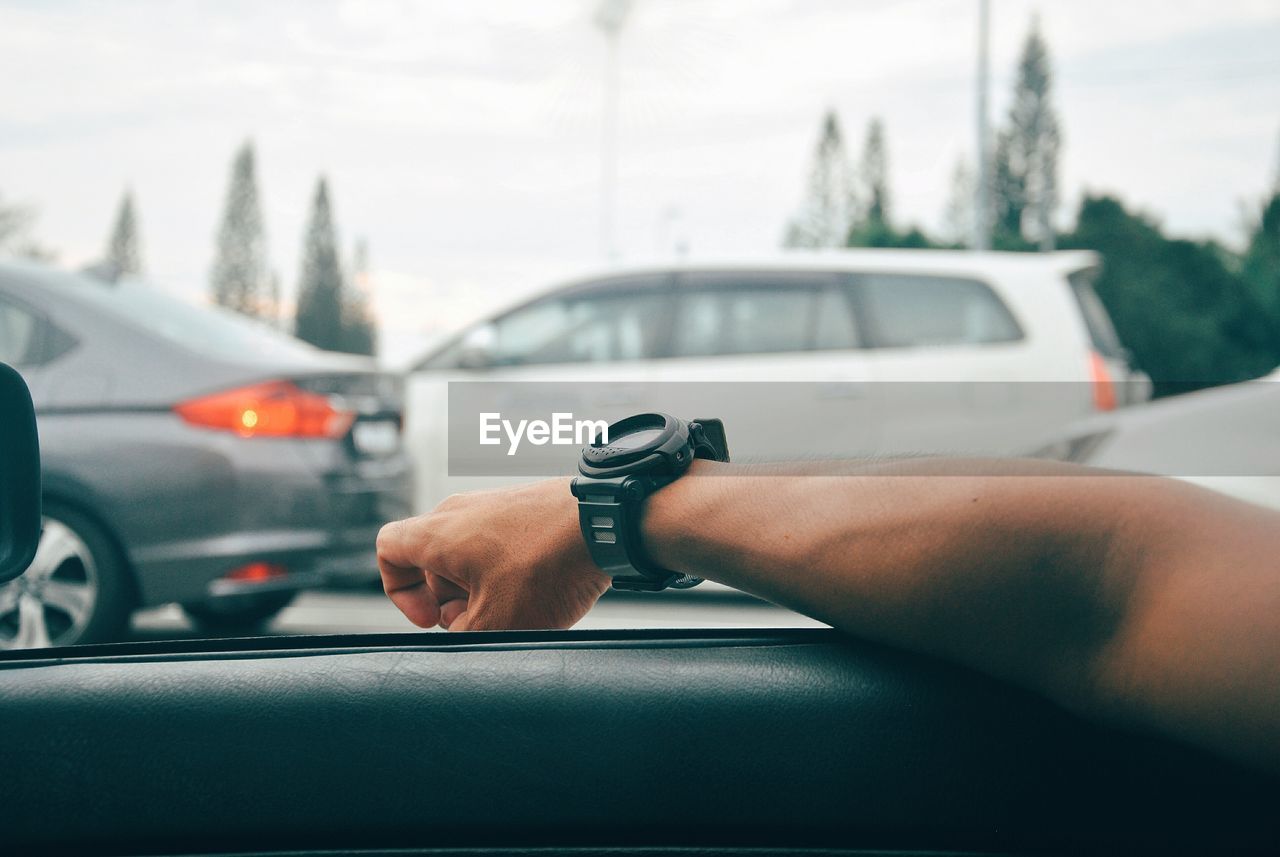 Cropped hand of person wearing wristwatch on car window