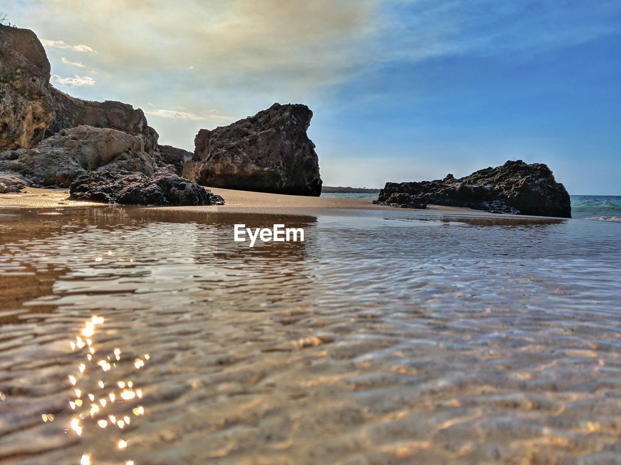 ROCK FORMATIONS ON BEACH AGAINST SKY