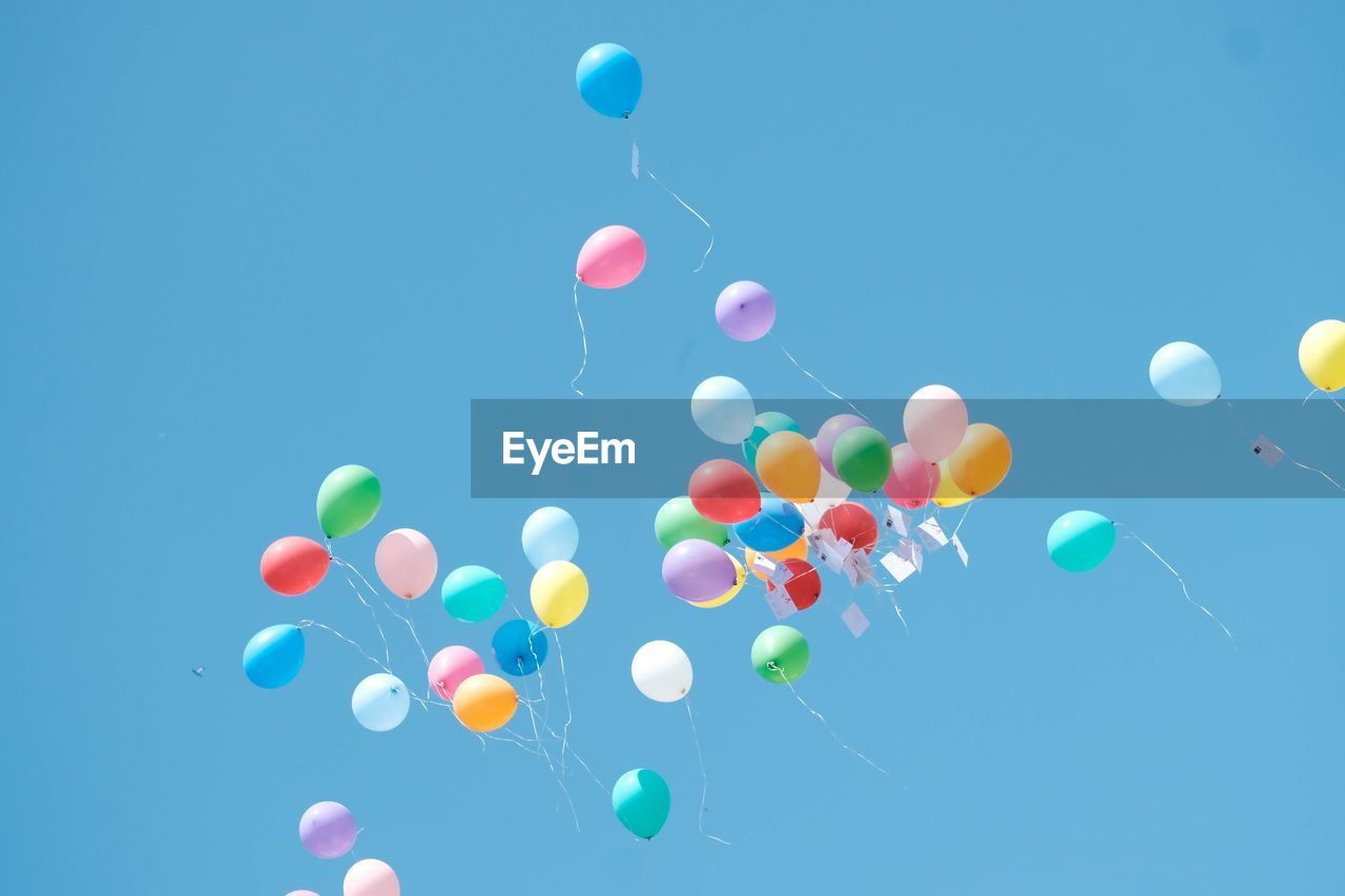 Low angle view of balloons against clear blue sky