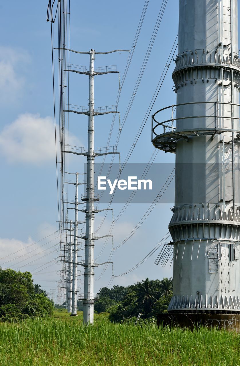 Image of a monopole high voltage transmission on a green grass hill.