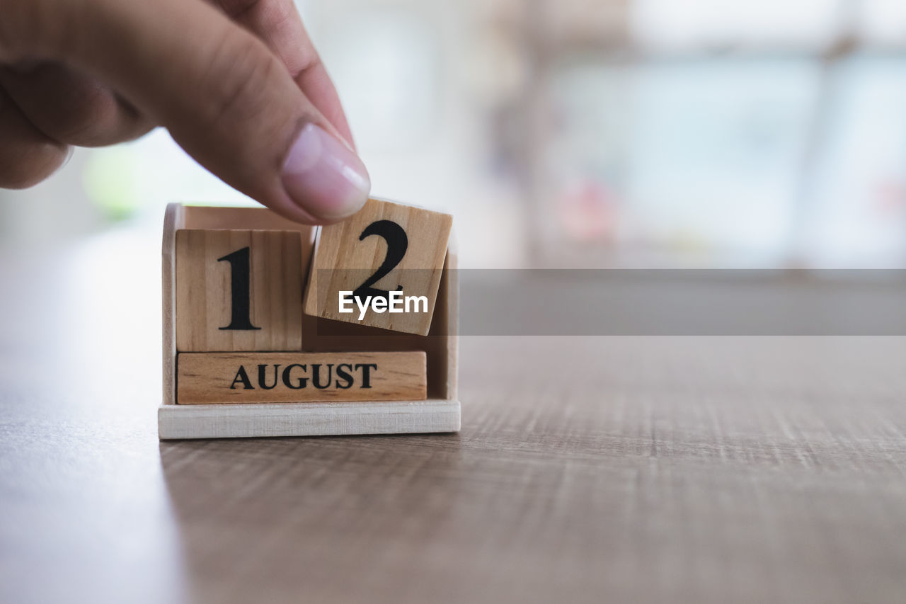 Cropped hand holding calendar on table