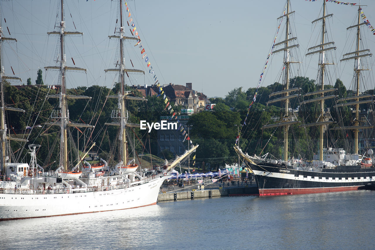 BOATS SAILING IN HARBOR AGAINST CLEAR SKY