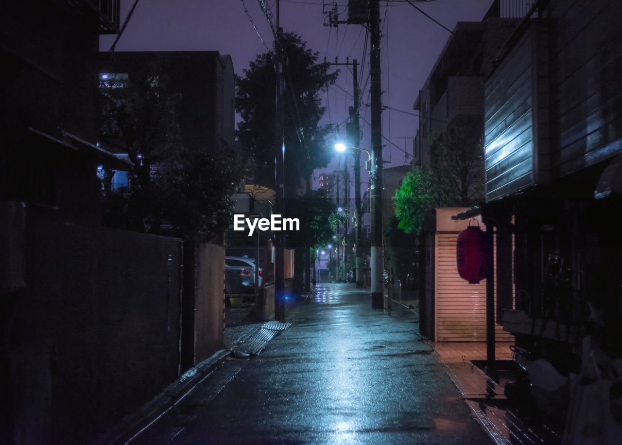 STREET AMIDST BUILDINGS AT NIGHT