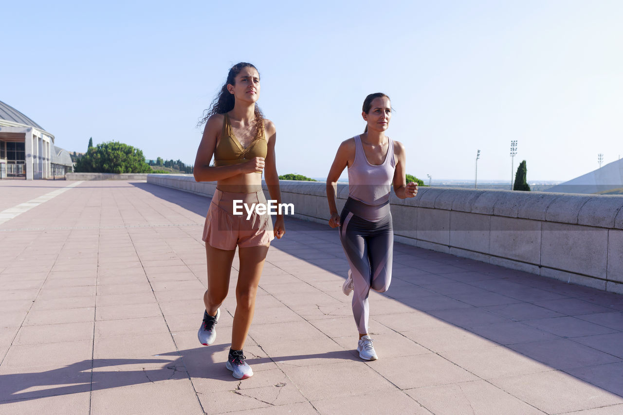 Daughter jogging with mother on sunny day