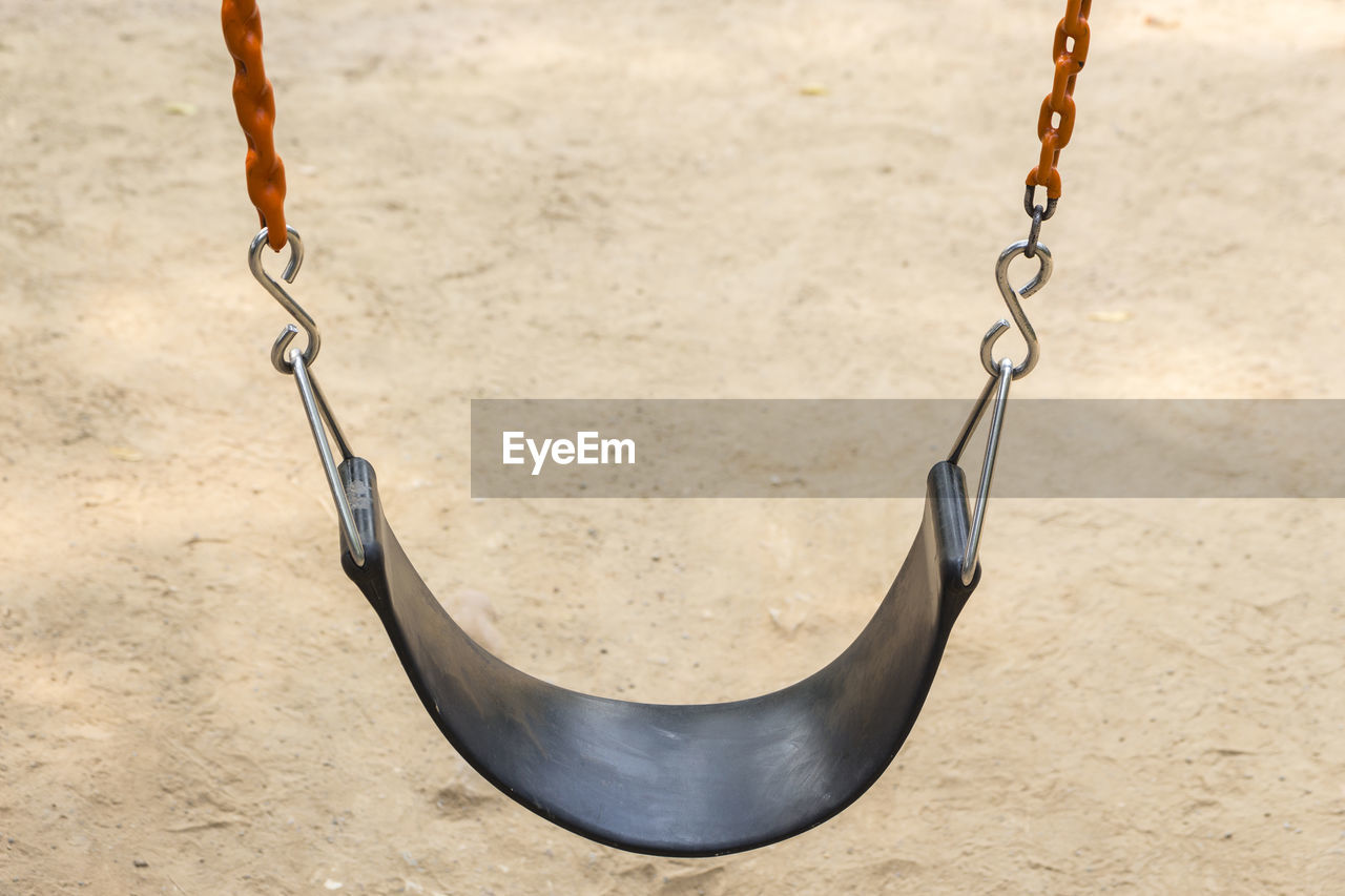 Black seat and red chain of swing in playground