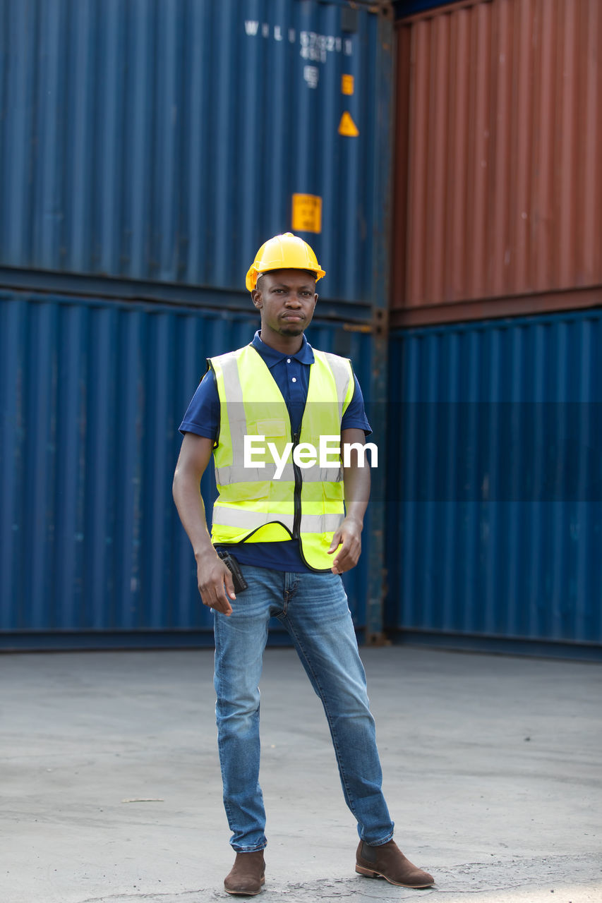 Full length portrait of young man standing at warehouse