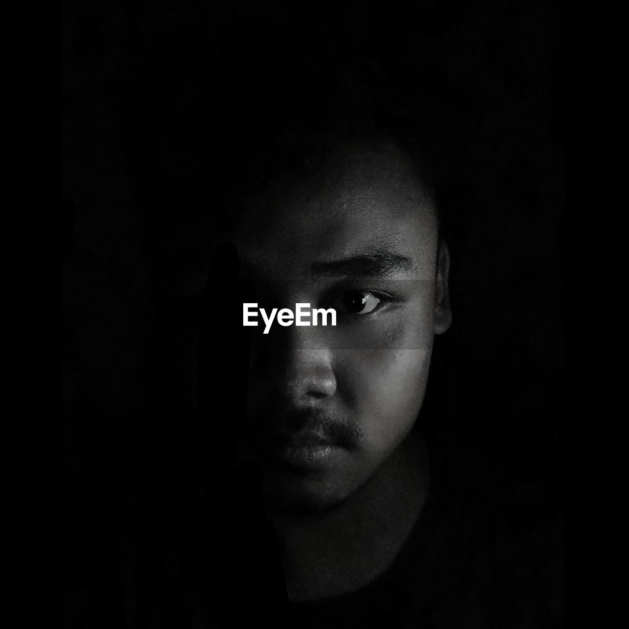 Close-up portrait of young man against black background