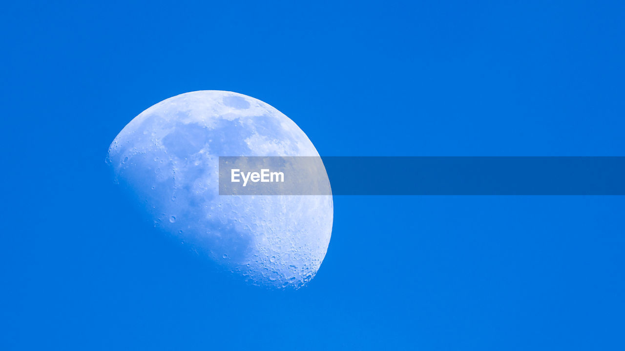LOW ANGLE VIEW OF MOON AGAINST CLEAR BLUE SKY AT NIGHT