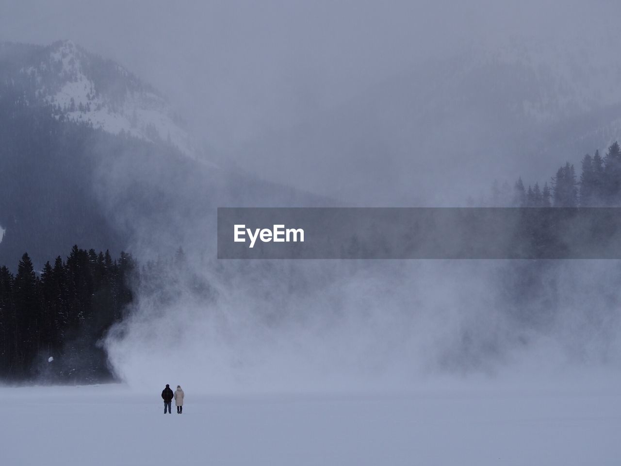 People on snow covered land against sky during winter