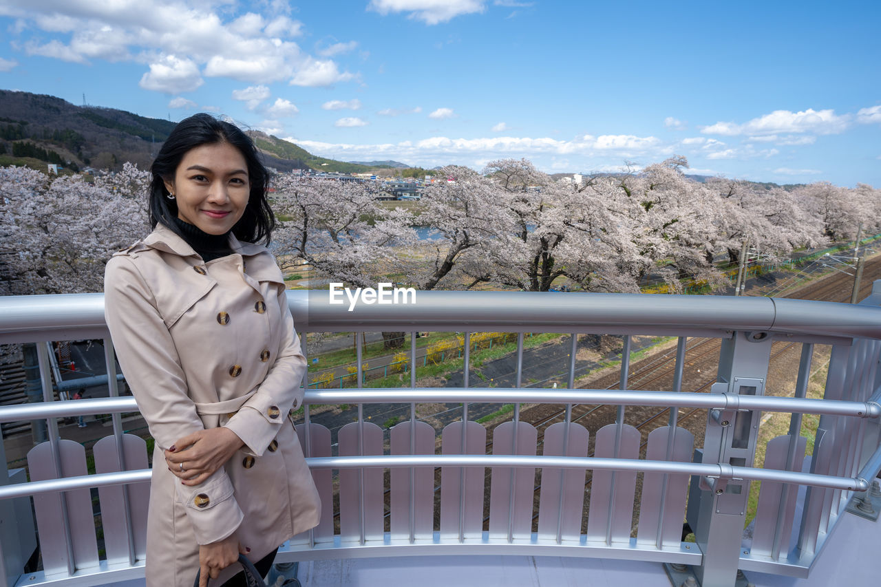 Woman standing by railing against sky