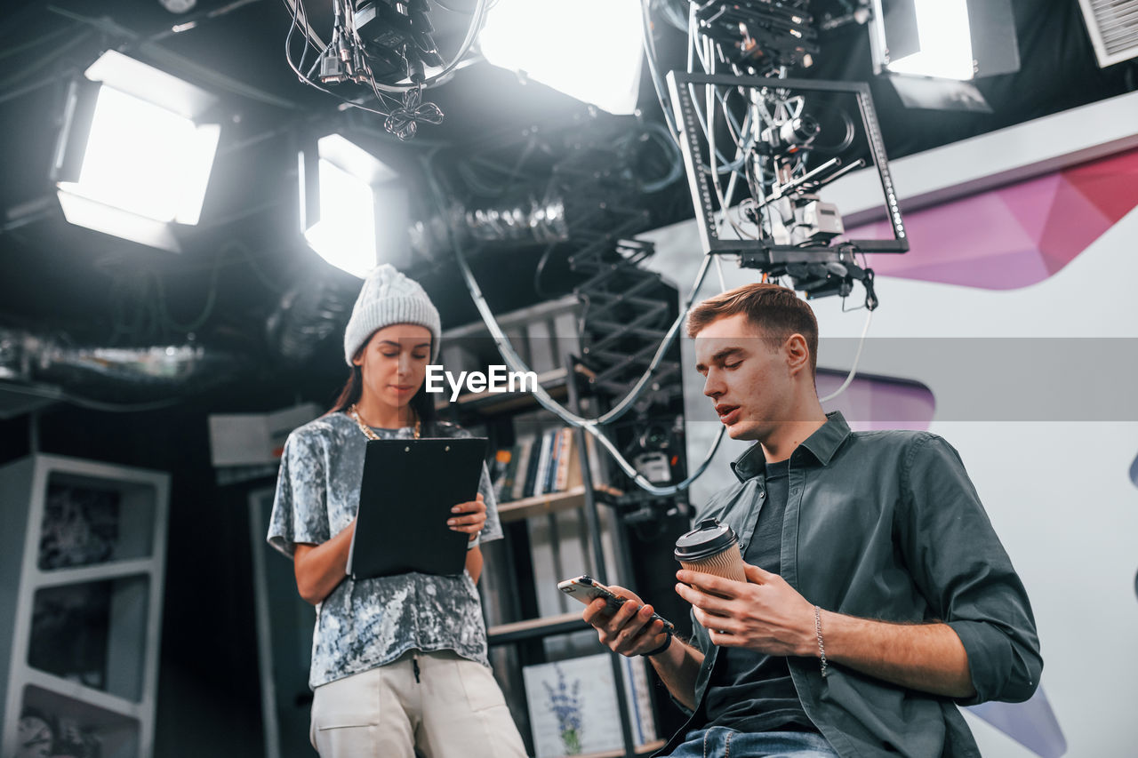 Young man is preparing for tv online broadcast. woman helps with make up.