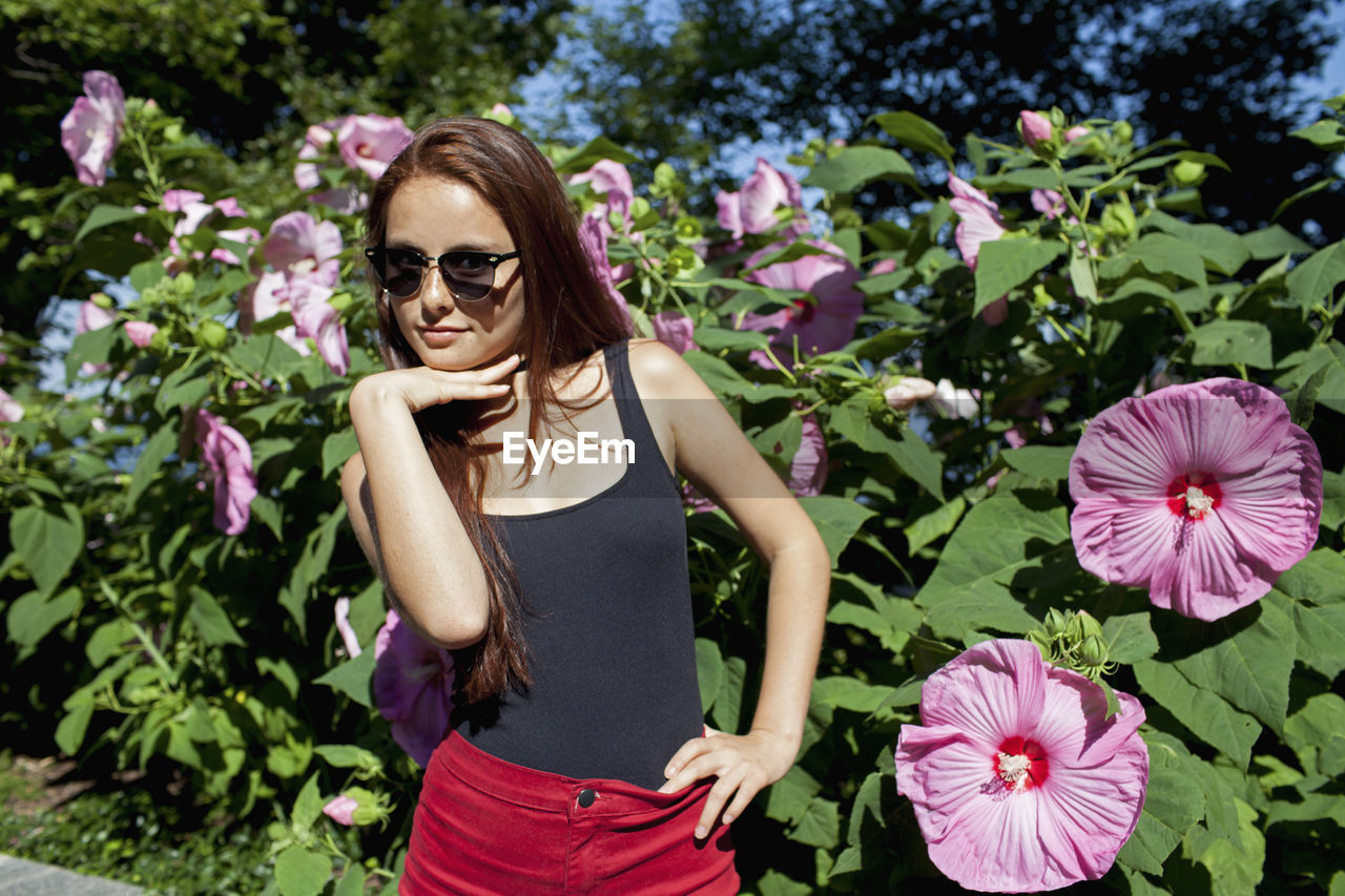 A young woman posing in front of a bush