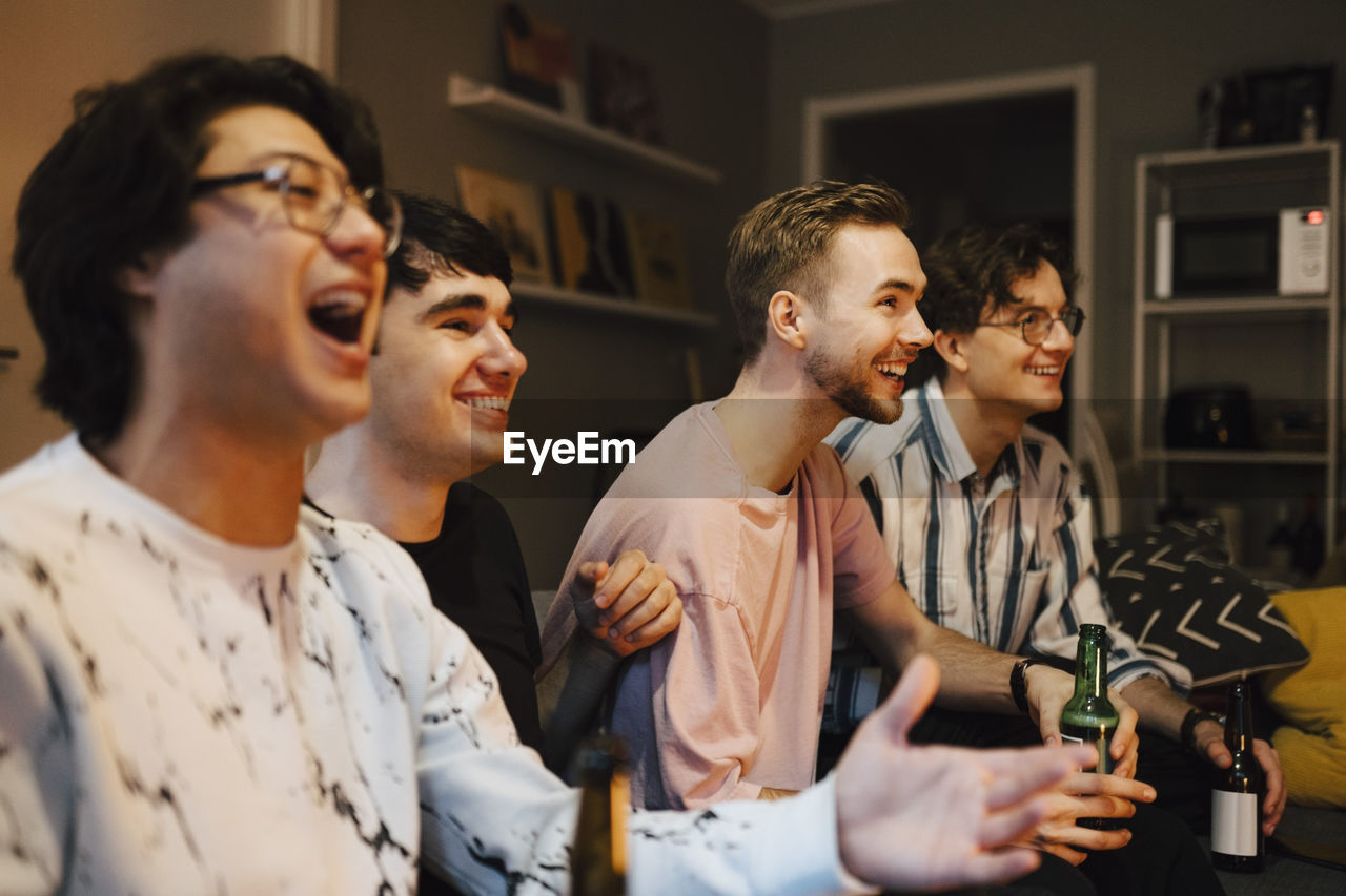 Excited multi-ethnic male friends watching sports at home