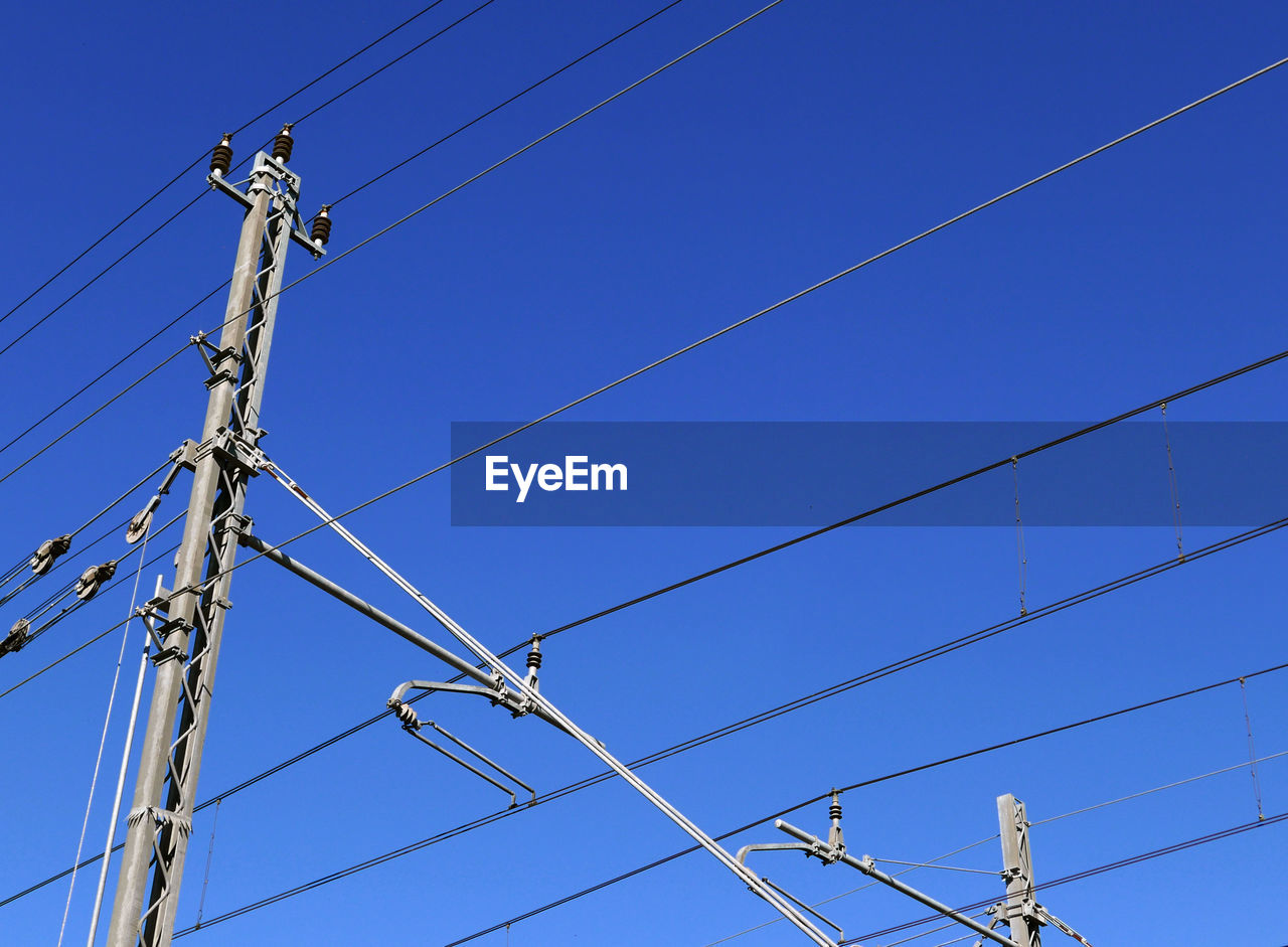 Intertwining of electric poles against the blue sky