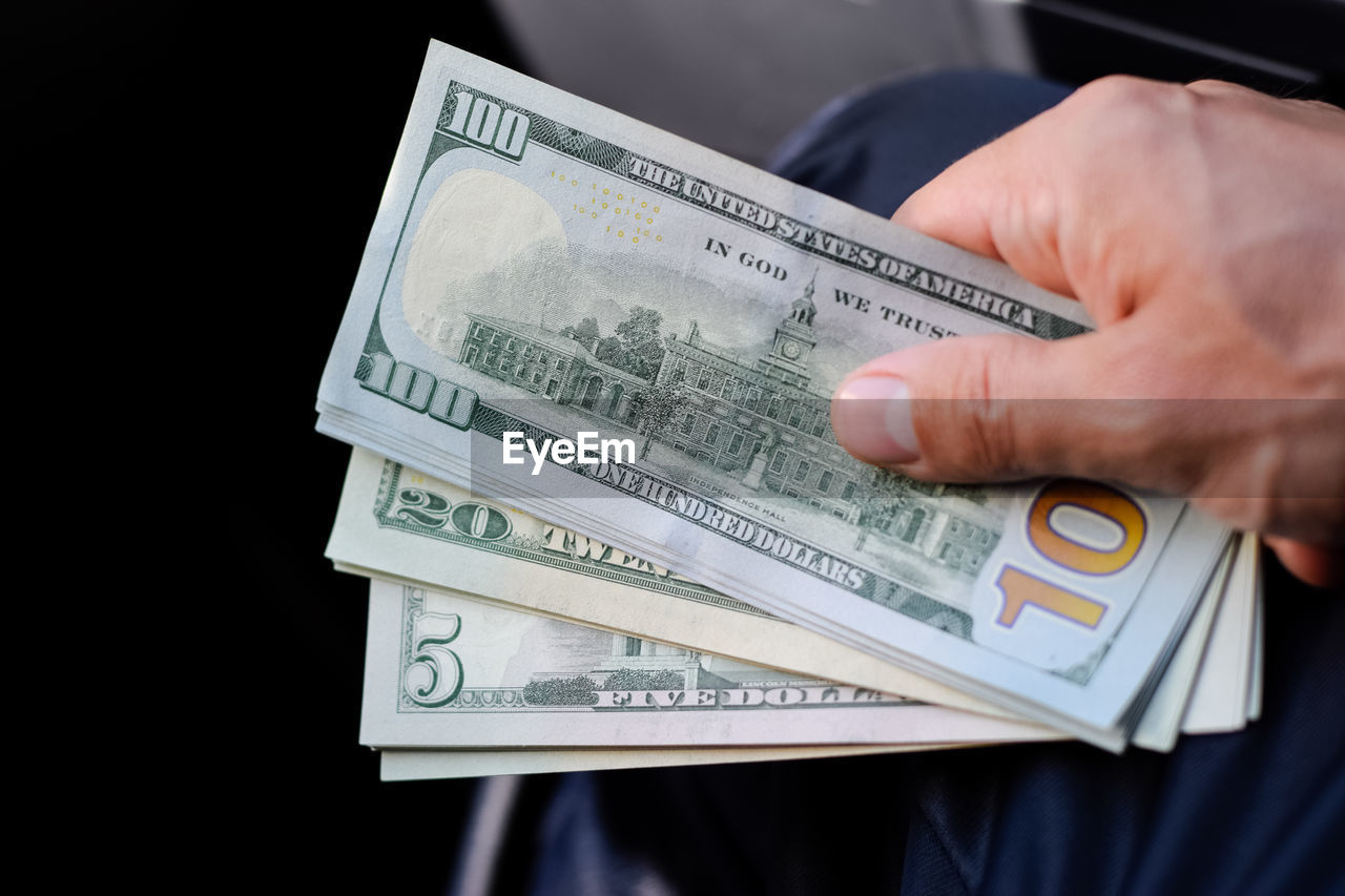 Midsection of man holding paper currency against black background