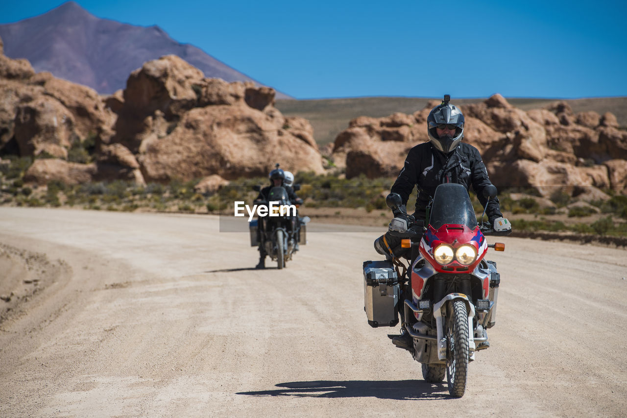 Two friends riding touring motorcycle's on dusty road in bolivia