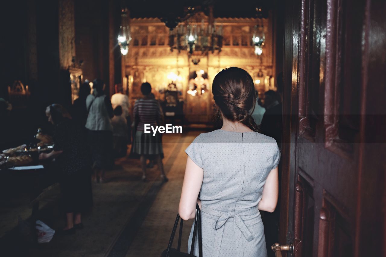 Rear view of woman standing by door at church