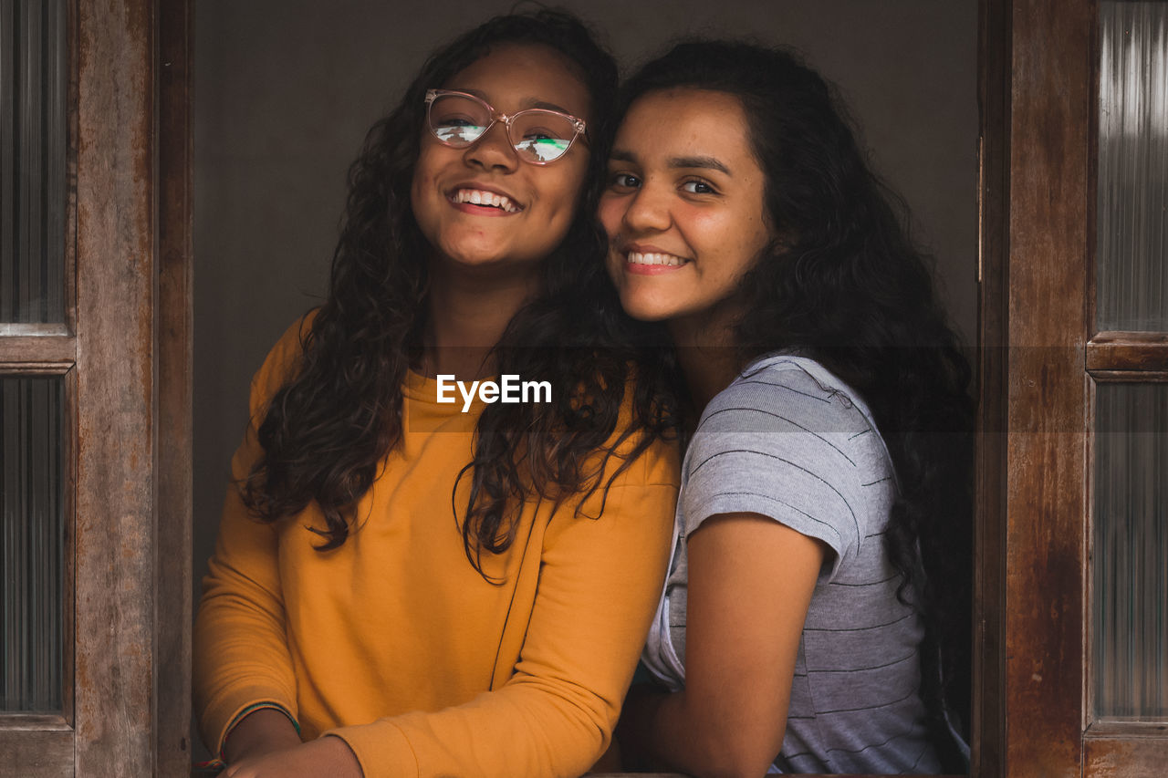 Portrait of smiling sisters by window