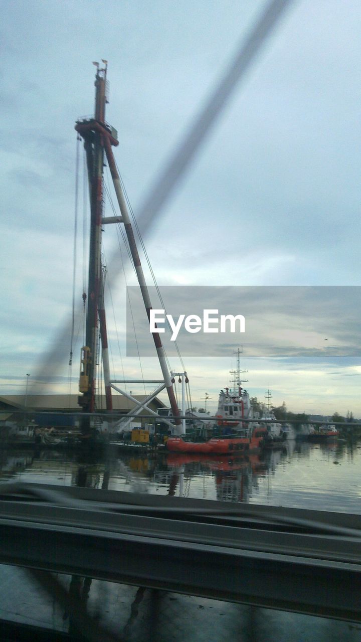 CRANES AT RIVER AGAINST SKY