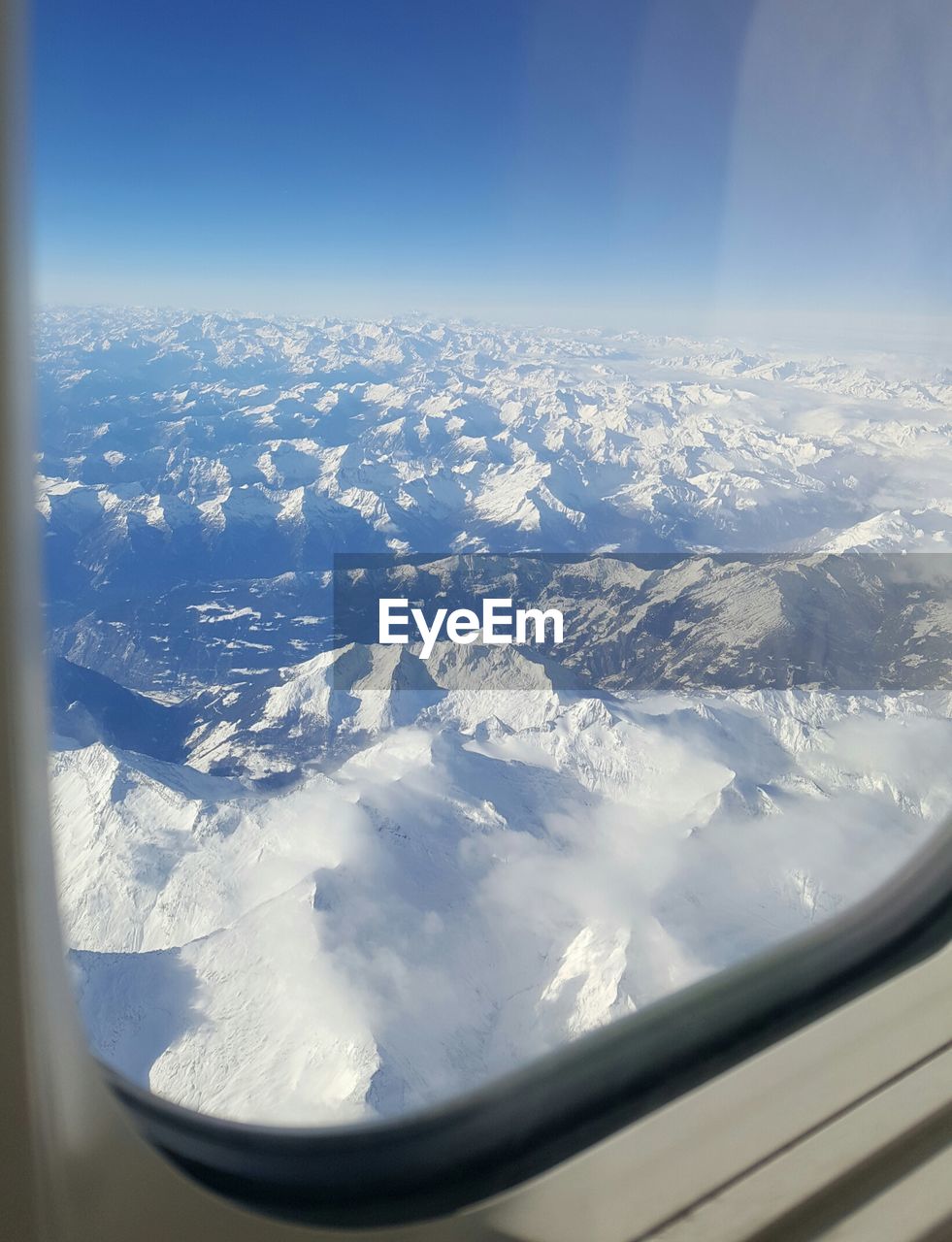 AERIAL VIEW OF CLOUDS OVER LANDSCAPE SEEN THROUGH AIRPLANE WINDOW