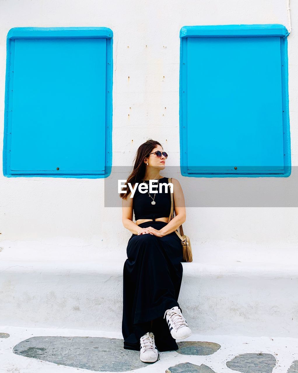 Full length of woman sitting against white wall