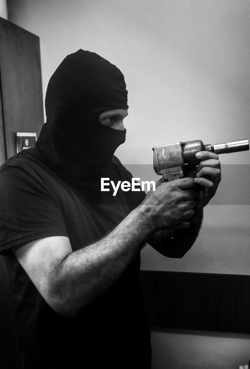 MAN HOLDING CAMERA WHILE STANDING IN KITCHEN