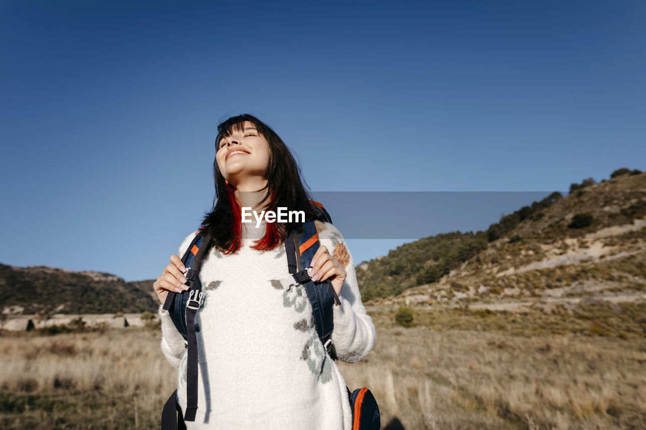 Serene woman standing below sky