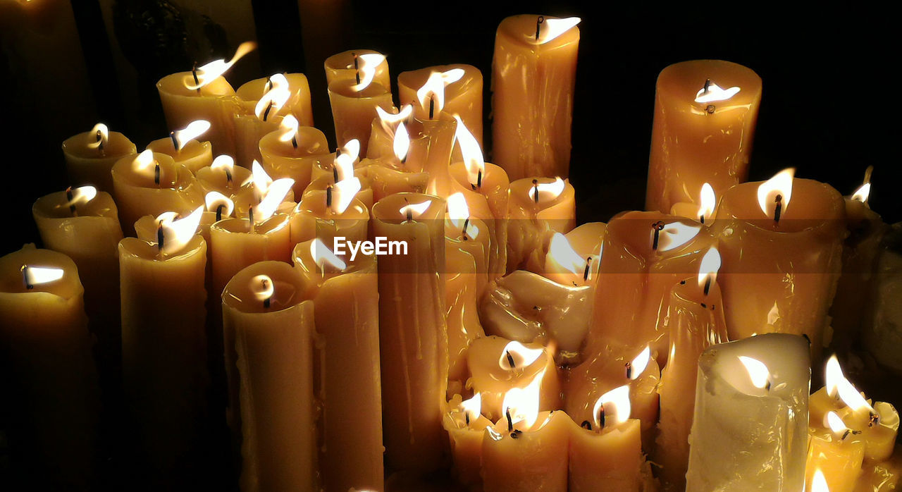 Close-up of lit candles in darkroom