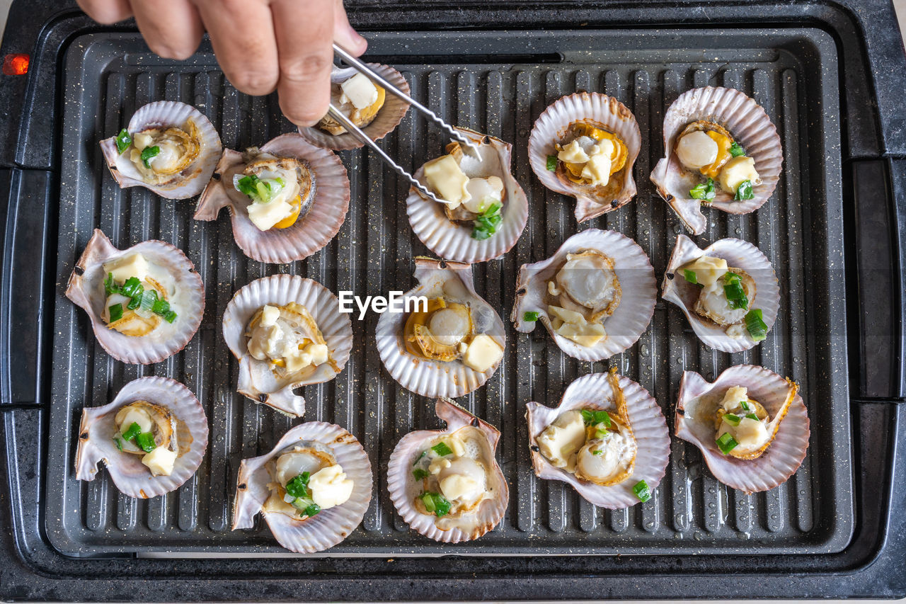 Grilling scallops with green onion and cheese on electric stove