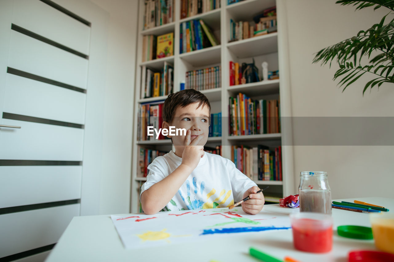 PORTRAIT OF BOY SITTING ON TABLE AT HOME