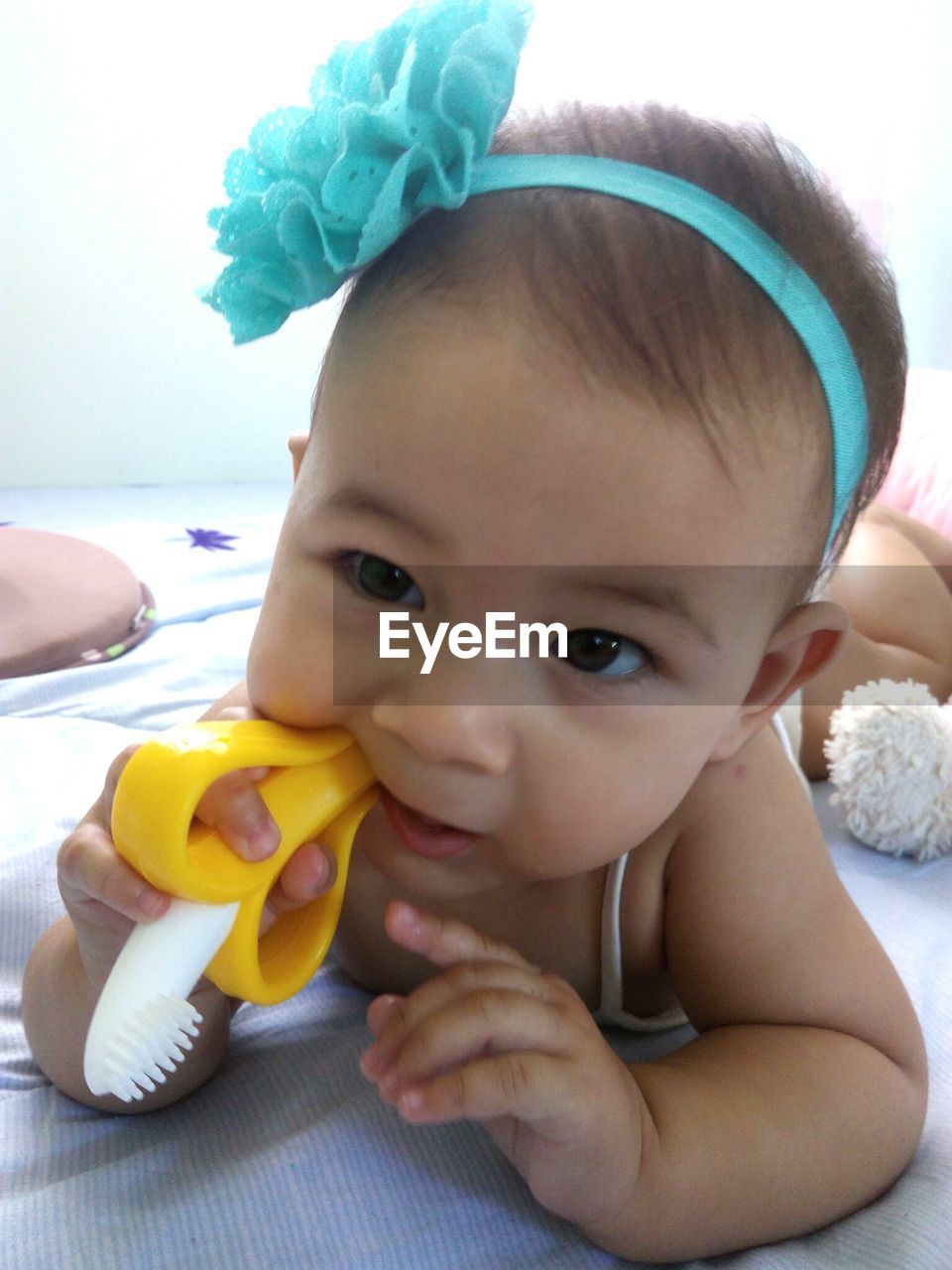 Close-up of cute baby girl holding toy on bed