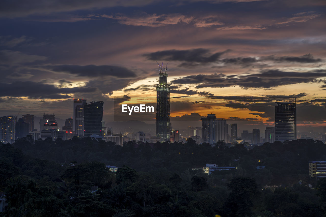 Illuminated buildings in city against sky during sunset