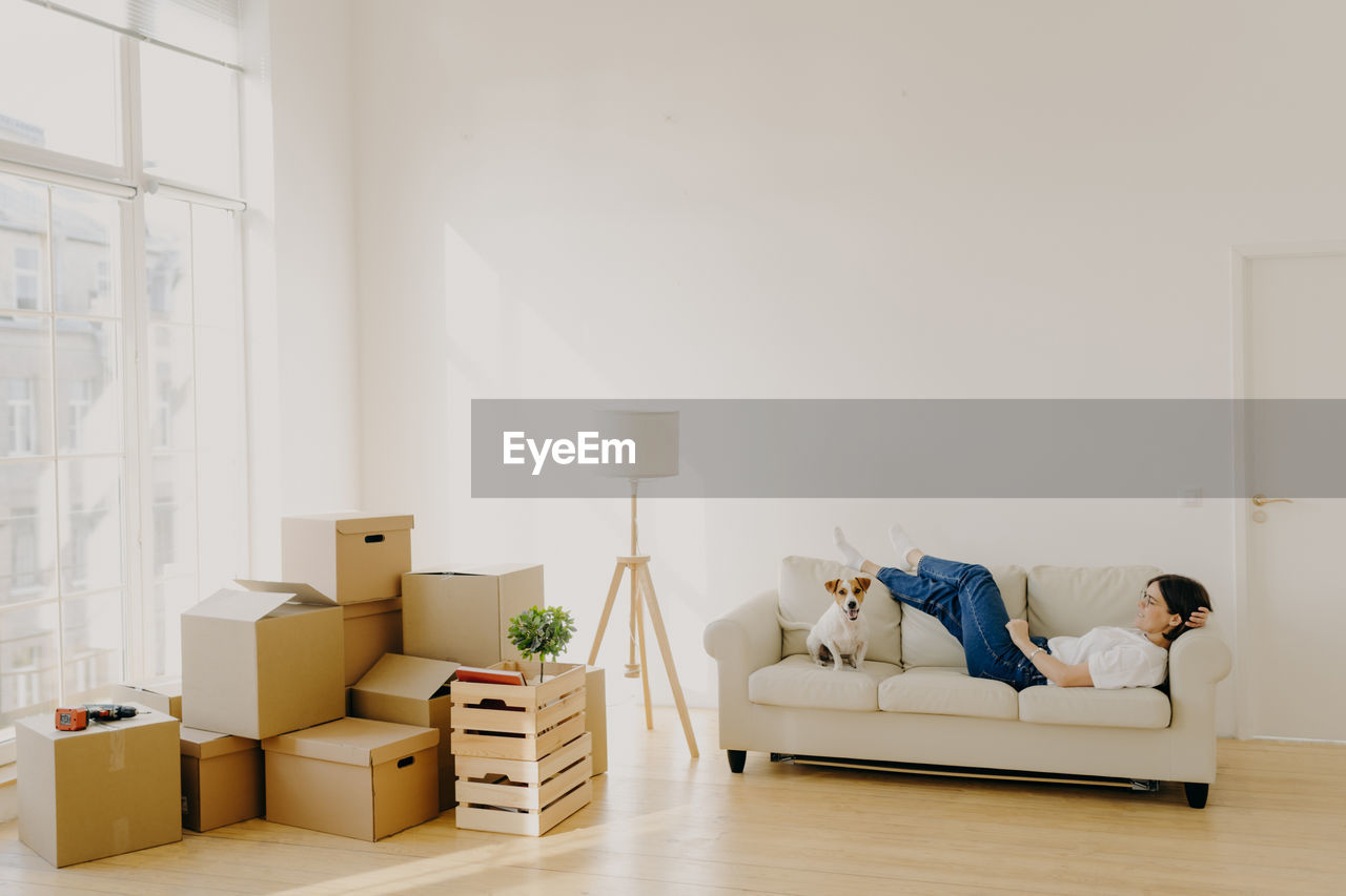 Woman with dog relaxing on sofa in new house