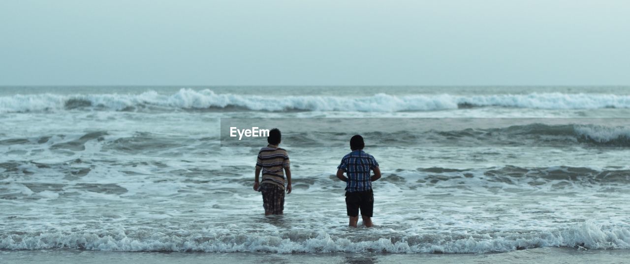 REAR VIEW OF MEN AT BEACH