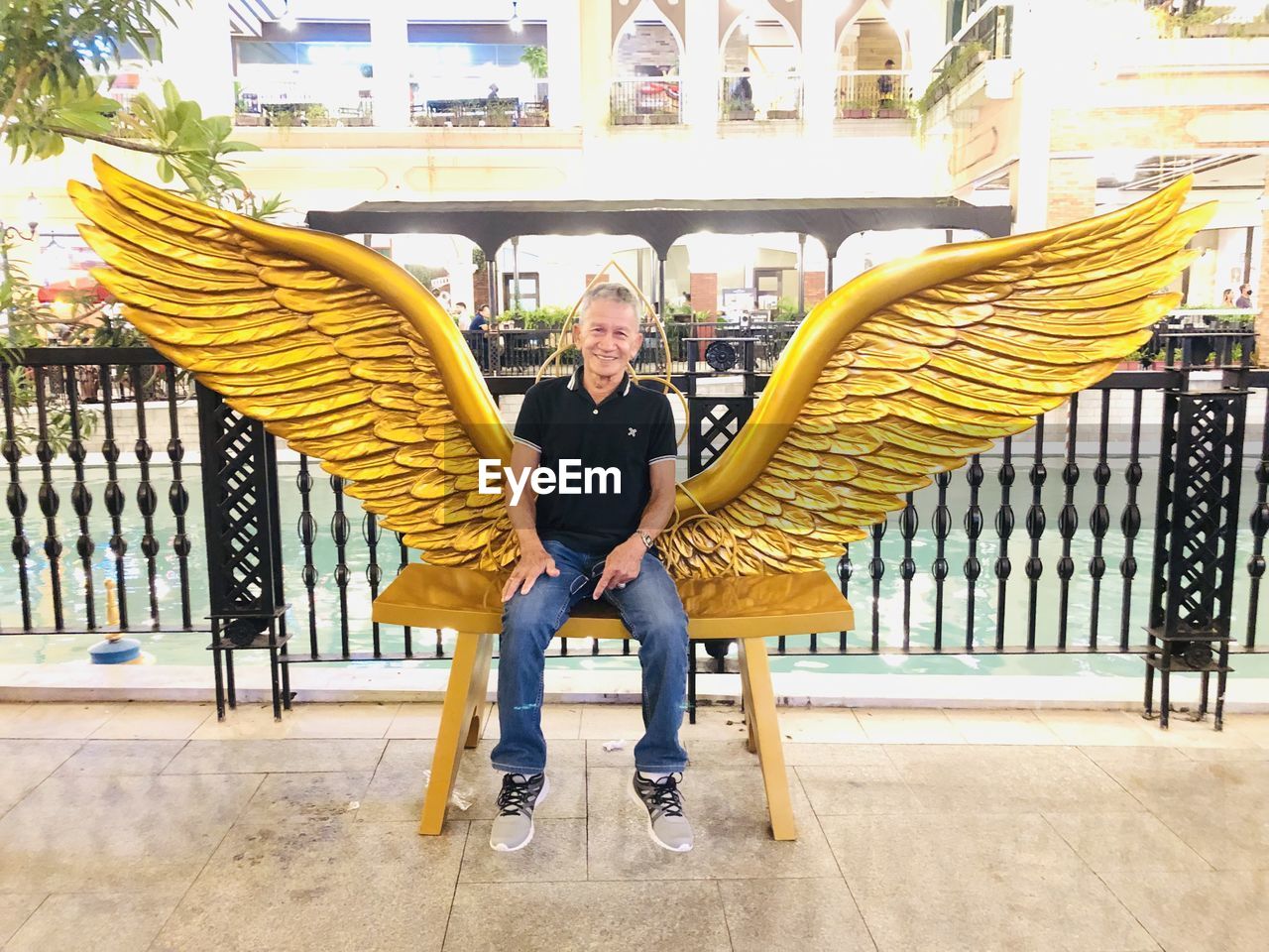 Low section of old man sitting on a bench with wings