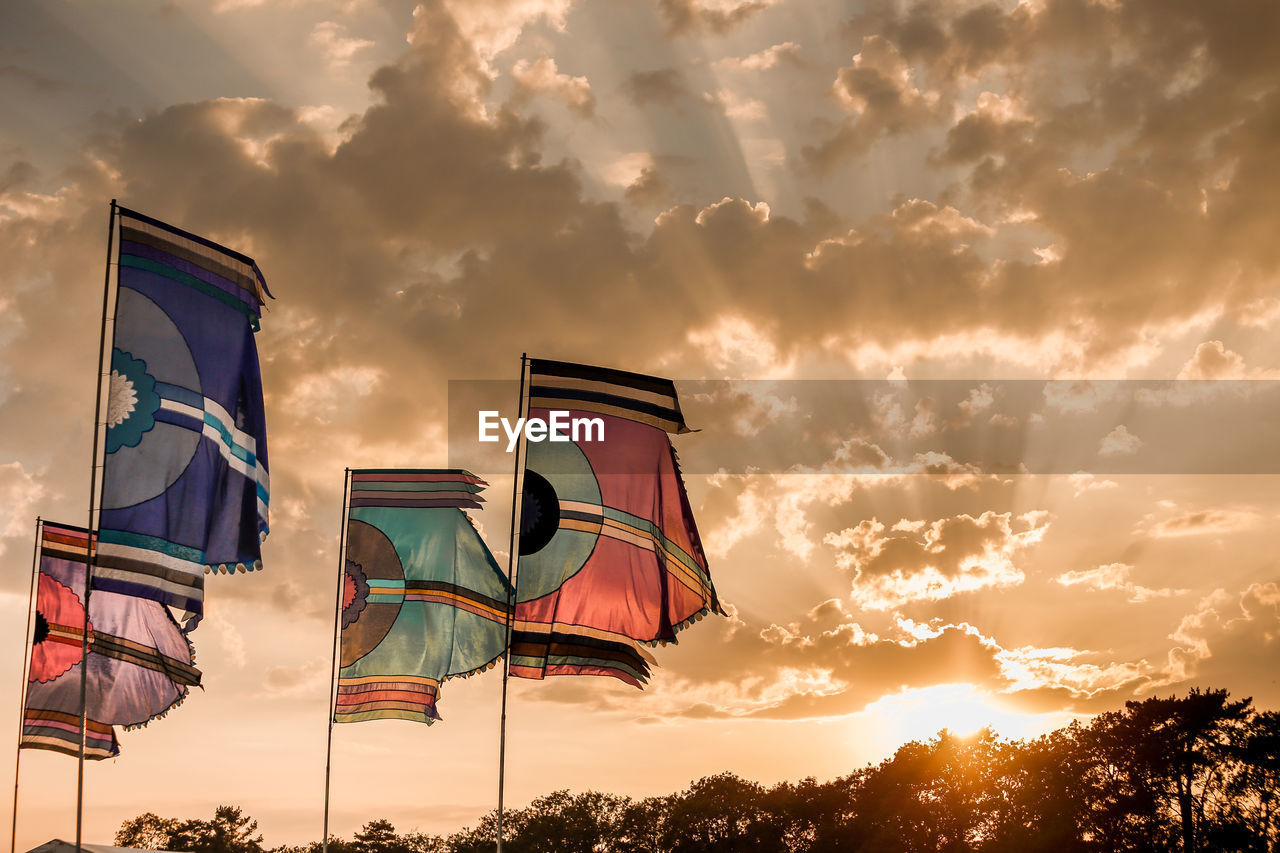 Low angle view of flags against cloudy sky during sunset