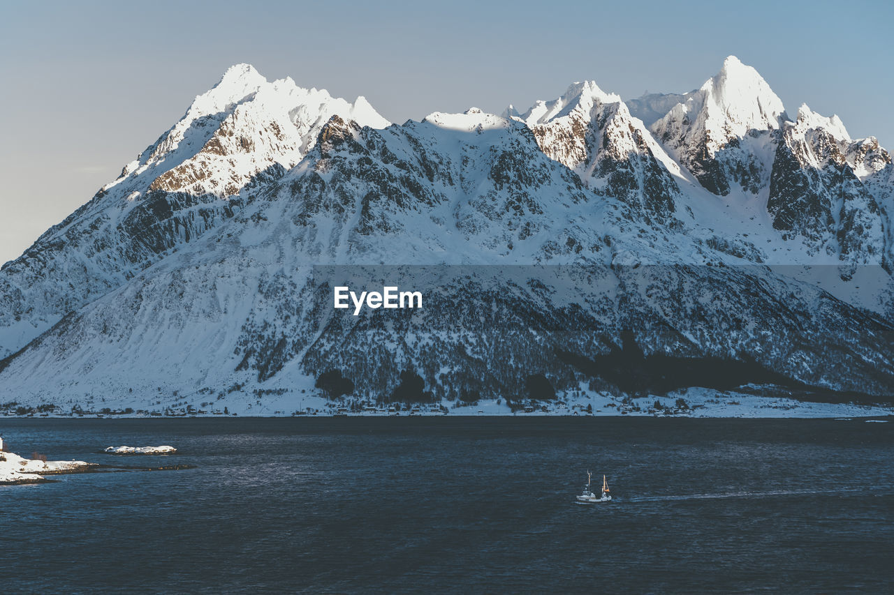 Scenic view of sea and snowcapped mountains against sky