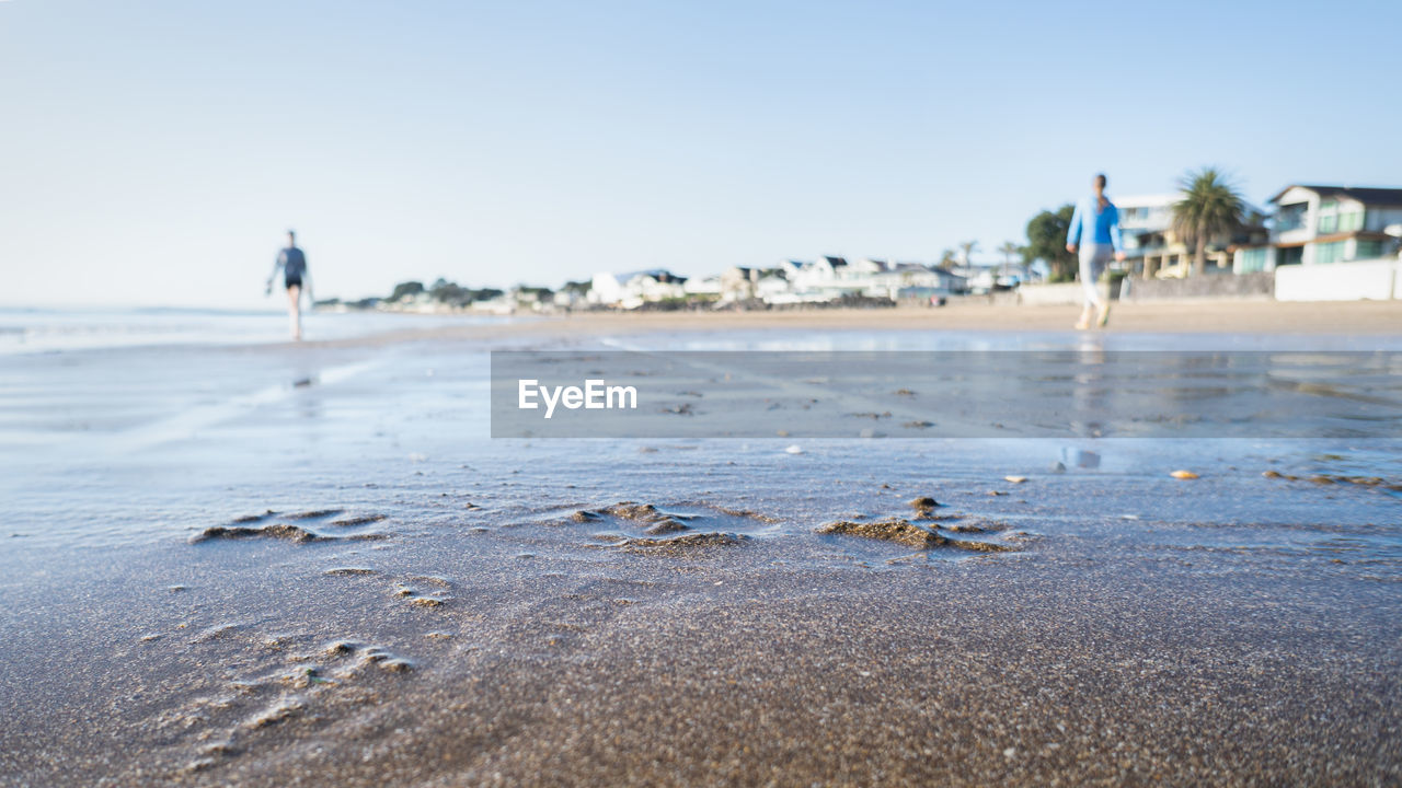 SURFACE LEVEL OF BEACH AGAINST CLEAR SKY