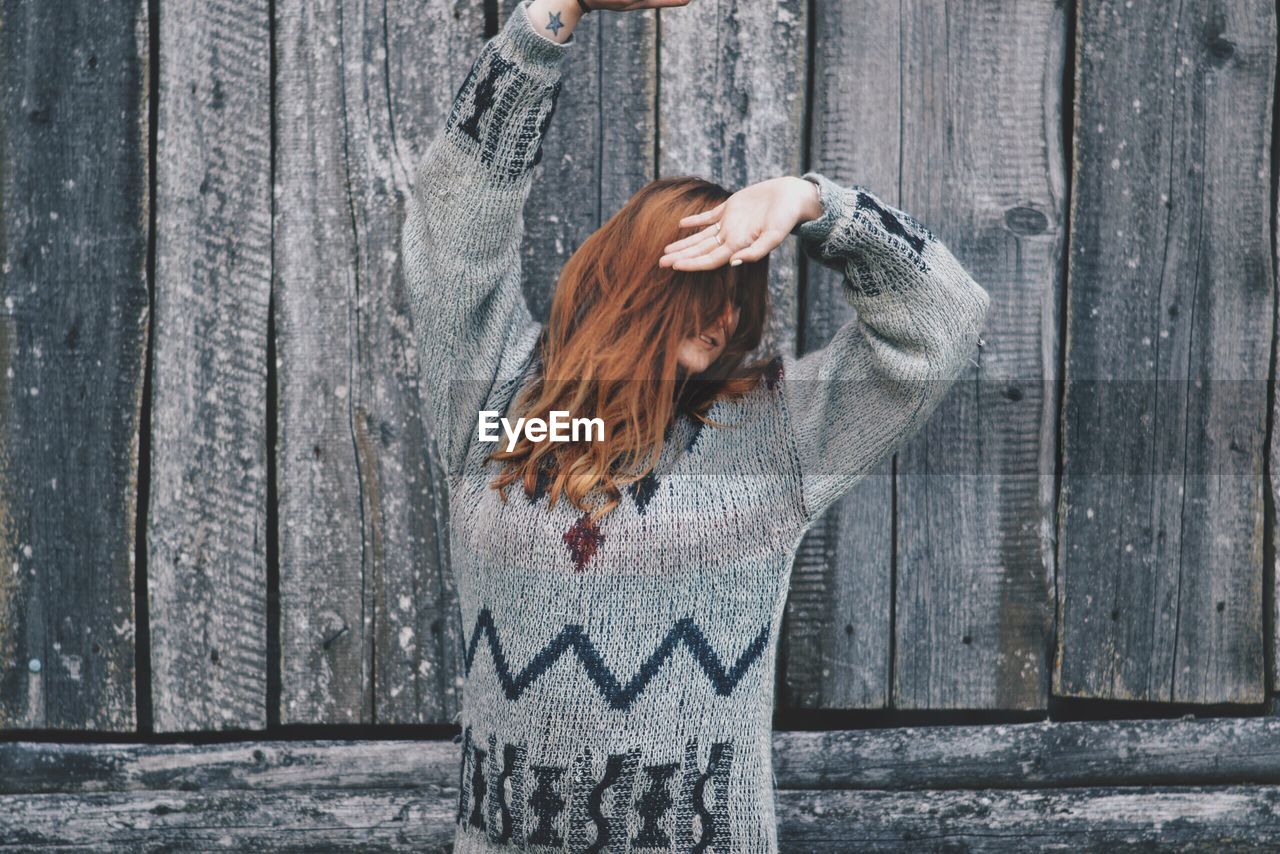 Woman in warm clothing standing against wall