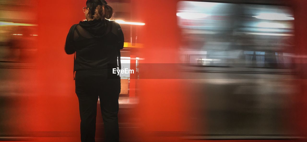 Rear view of woman standing by moving train