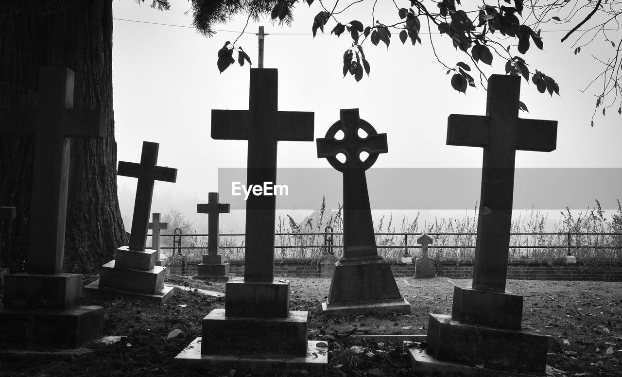 Cross on cemetery against sky