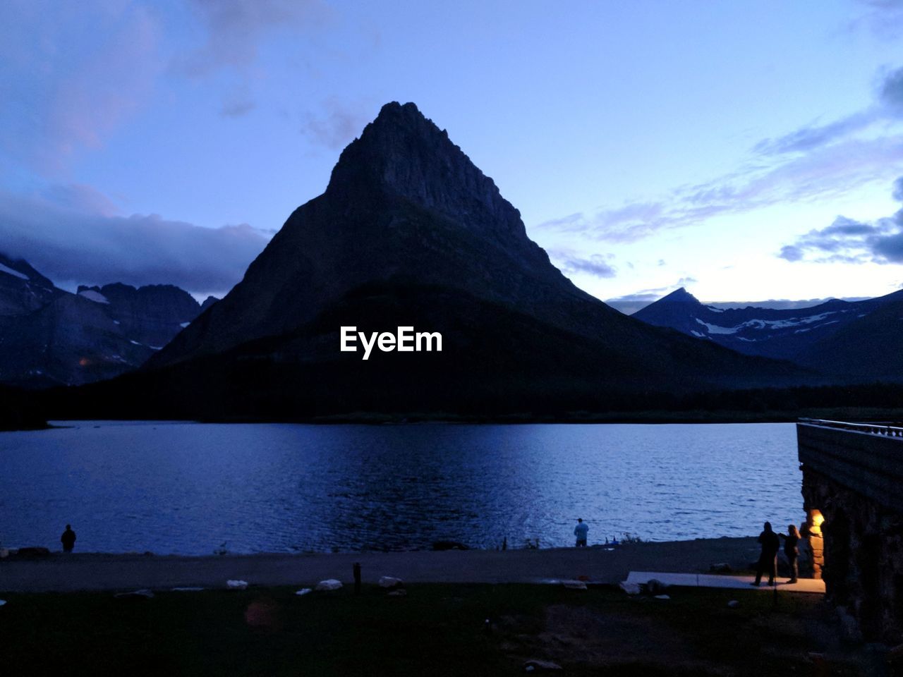 Scenic view of lake by silhouette mountains against sky