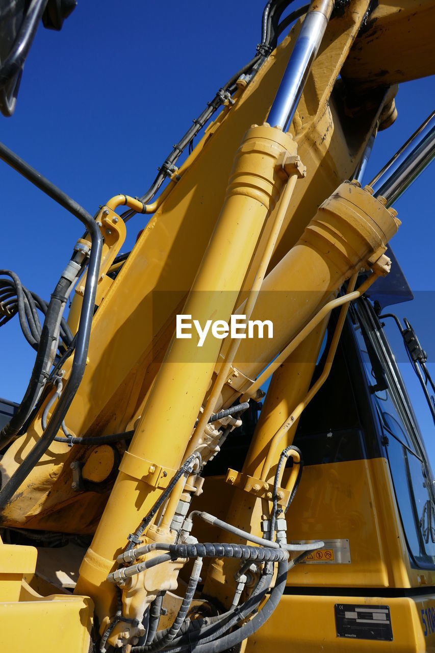 Low angle view of earth mover against clear sky