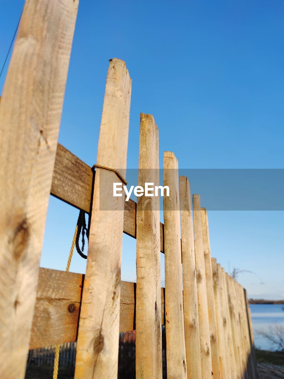 Low angle view of fence against clear blue sky